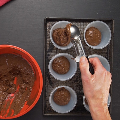 Scoops of cake mix being put into baking cups