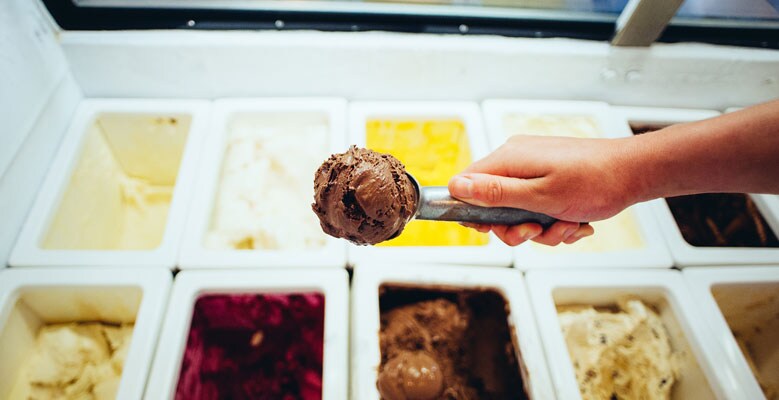 hand scooping multiple flavors of ice cream
